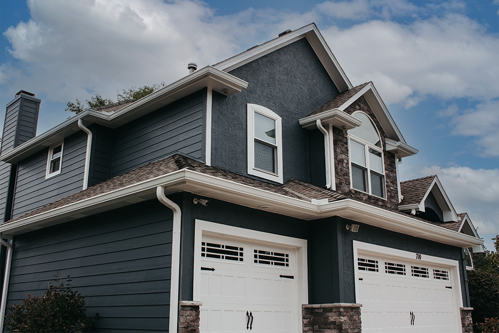 Two-story Lincoln Nebraska home with deep navy lap siding, white trim, stone accents, and steep gabled roofline